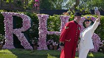 Blooming lovely: A visitor wearing floral themed headwear takes a selfie with Chelsea Pensioner Norman Bareham at the Chelsea Flower Show in London