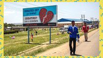 People pass by an AIDS Healthcare Foundation awareness billboard in Maputsoe, Lesotho, on January 31, 2020.