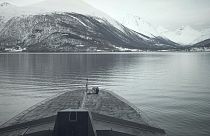 A French sailor sits at the bow of the French navy frigate Normandie during a patrol in a Norwegian fjord, north of the Arctic circle, Friday March 8, 2024.