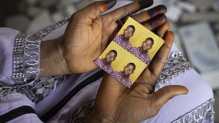 Mariama Sylla, sister of Ousmane Sylla, holds photos of him in their house at Matoto Bonagui, a suburb of Conakry, Guinea, Monday, April 8, 2024.