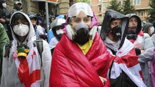 Demonstrators in gas masks stand near the Parliament building during an opposition protest against "the Russian law" in the center of Tbilisi, Georgia, on Monday, May 13, 2024