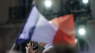 Behind a French flag, French President and centrist candidate Emmanuel Macron speaks during a campaign rally, Saturday, April 16, 2022 in Marseille, southern France.