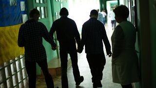 Residents walk along a corridor after lunch time in a facility for people with mental and physical disabilities in the village of Tavriiske, Ukraine, Tuesday, May 10, 2022.