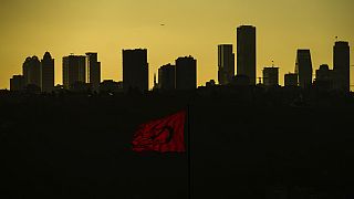 FILE - The sun sets behind high buildings of a financial business area in Istanbul, Turkey, Friday, March 22, 2024. 