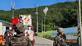 Balloons with trash presumably sent by North Korea, hang on electric wires as soldiers stand guard in Muju, South Korea.