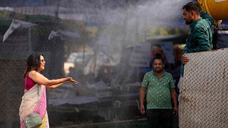 A polling official enjoys a cooling spray of water under intense heat on the eve of the fifth phase of polling in national election in Lucknow, India, Sunday May 19, 2024.