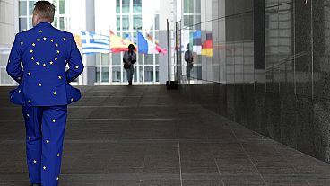 A man wears a suit in the EU colors as he walks outside the European Parliament