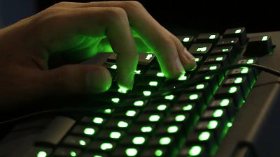 A person's hand rests on an illuminated keyboard.