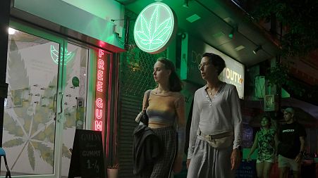 Tourists pass by a newly-legal cannabis shop, 10 August 2022, in Bangkok, Thailand. 