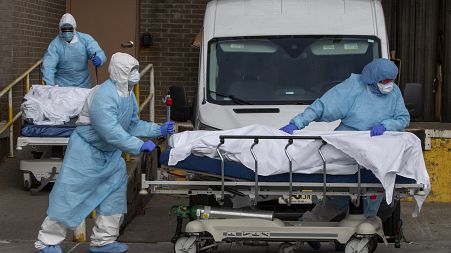 Medical personnel wearing personal protective equipment remove bodies from a medical centre in New York, 2020.