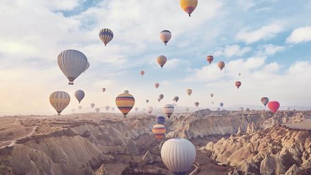 Hot air balloons, carrying tourists, rise into the sky above the "fairy chimneys" in Cappadocia, central Türkiye.