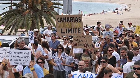 People march past a beach during a demonstration against overtourism which affects the local population with inaccessible housing, in the Canary Islands.