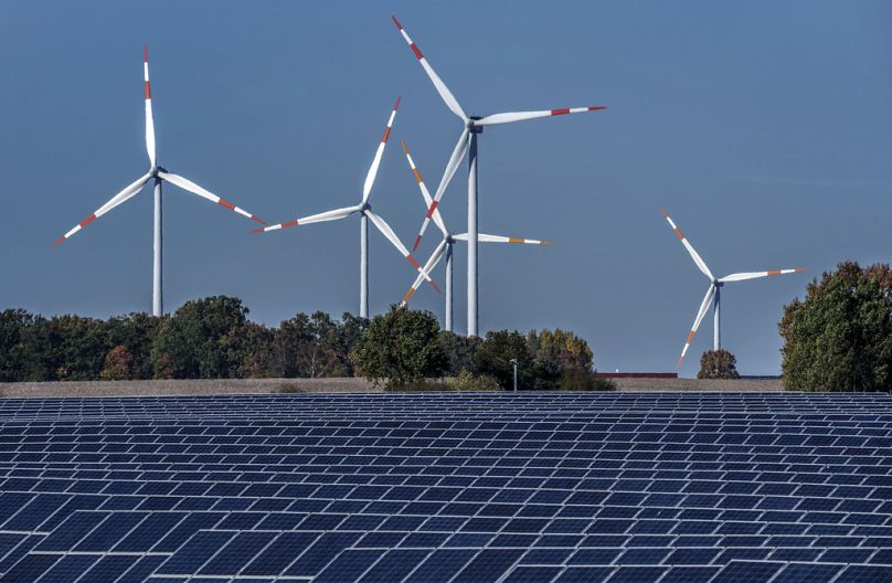 Wind turbines turn behind a solar farm in Rapshagen, October 2021